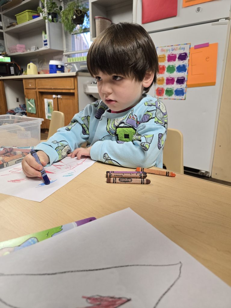 child coloring with crayons