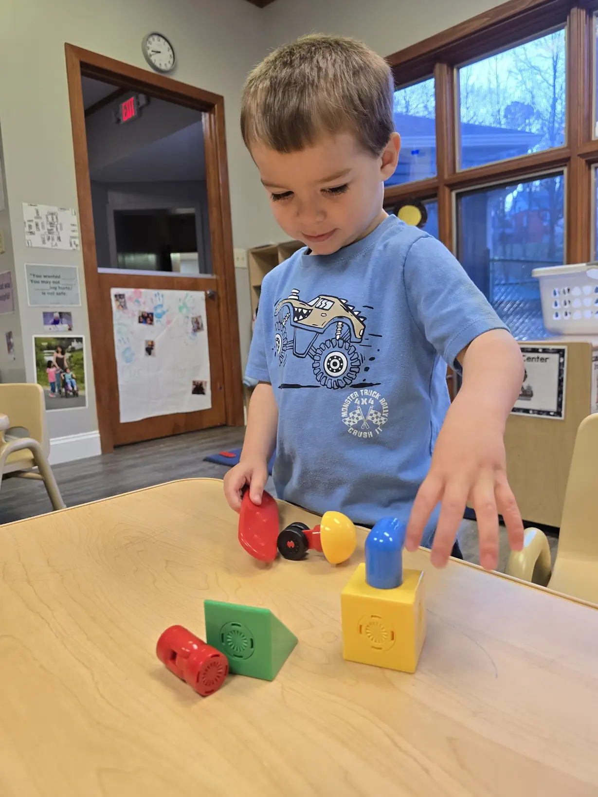 a child wearing printed blue shirt playing with colorful block set on the table