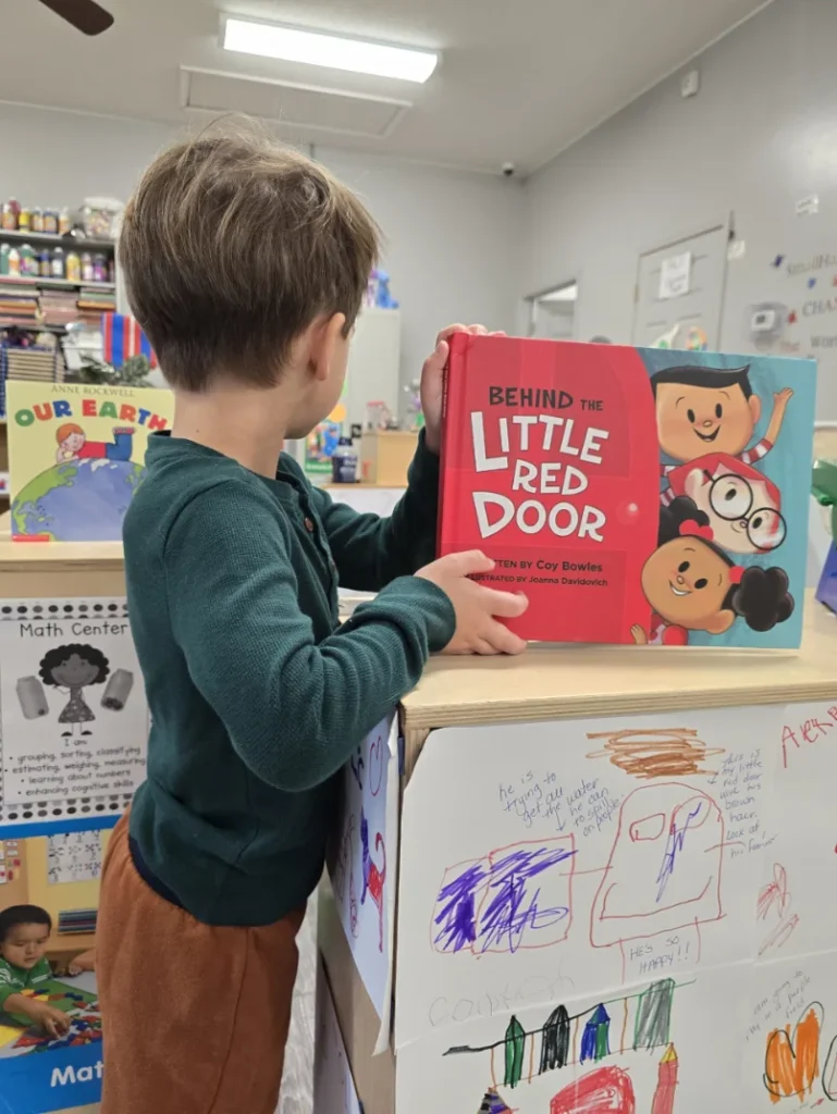 child holding a red book in a room in Redland, SC