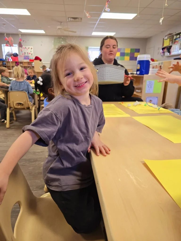 A little girl at a daycare table surrounded by colorful paper, focused on her creative activities in Boiling Springs, SC